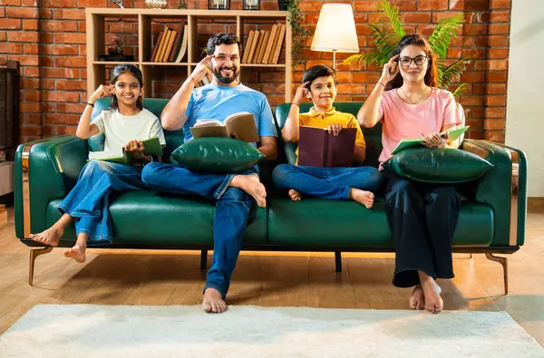 Aile kitap tanıtımını evde rahat bir kanepede otururken yapıyor. Çocuklu Asyalı genç bir çift okuma alışkanlığı geliştirmenin önemini anlatıyor. Zeka ve iç mekanda gelişim.