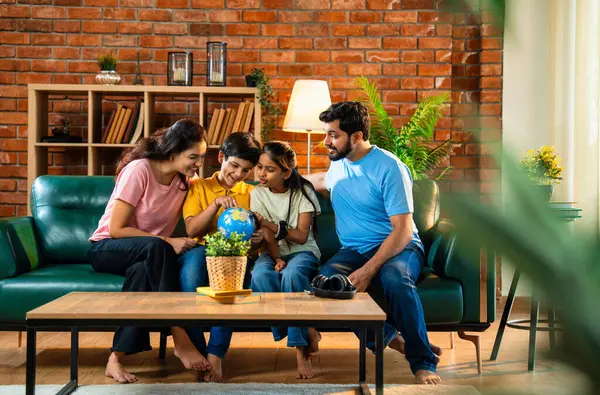 Aile, dünya üzerinde birlikte araştırma yapıyor. İki çocuklu Hintli ebeveynler, ülkelerinin şehirlerini belirlemek için oyuncak dünya modeliyle eğitimsel coğrafya oyunu oynarken evde kaliteli zaman geçiriyorlar.