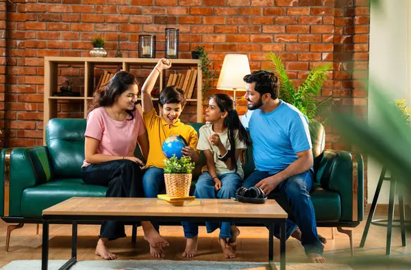 Aile, dünya üzerinde birlikte araştırma yapıyor. İki çocuklu Hintli ebeveynler, ülkelerinin şehirlerini belirlemek için oyuncak dünya modeliyle eğitimsel coğrafya oyunu oynarken evde kaliteli zaman geçiriyorlar.