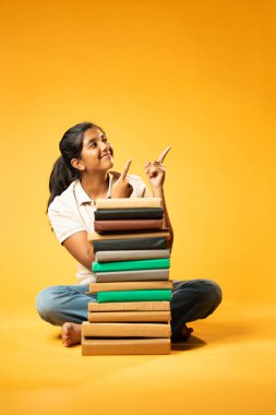 Kitap Yığını, Neşeli Hintli Genç Kız Sarı Kusursuz Özgeçmiş, Öğrenme, Okul Kavramları ve Akademik Mükemmellik Üzerine Eğitim Kitapları Yığını 'nda Mutlulukla Gösteriyor