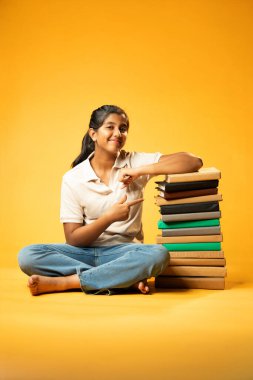 Kitap Yığını, Neşeli Hintli Genç Kız Sarı Kusursuz Özgeçmiş, Öğrenme, Okul Kavramları ve Akademik Mükemmellik Üzerine Eğitim Kitapları Yığını 'nda Mutlulukla Gösteriyor