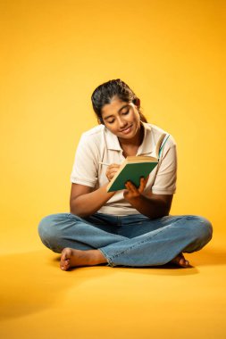 Kitap yazmakta, Hintli Asyalı Kız Derinlemesine Düşünerek Oturmakta ve Ders Çalışırken Not Almakta, Odaklanma ve Merakı Göstermekte Öğrenme veya Ödevde Etkinlik Göstermekte