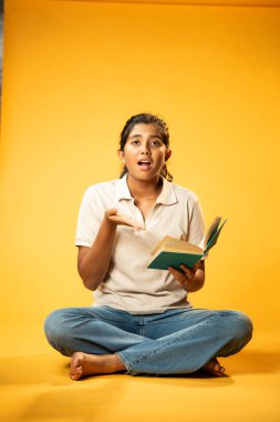 Kitap Okuma, Gergin Hintli Genç Kız Sarı Kusursuz Arkaplanda Oturarak Endişe Gösteriyor, Sınav ve Korku Duyuyor Üzgün Yüz İfadesi ve Düşük Özgüven ile Yalnız Çalışırken