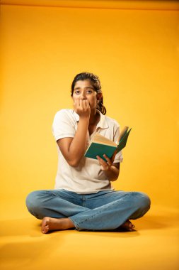 Kitap Okuma, Gergin Hintli Genç Kız Sarı Kusursuz Arkaplanda Oturarak Endişe Gösteriyor, Sınav ve Korku Duyuyor Üzgün Yüz İfadesi ve Düşük Özgüven ile Yalnız Çalışırken