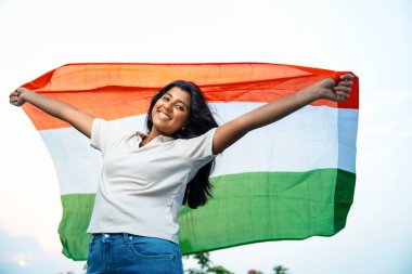 Elinde Hint Bayrağı, Neşeli Genç Kız Rüzgarda Üç Renkli Flütçüler, Mavi Gökyüzü Altında Ulusal Gurur ve Vatanseverlik Gösteren Mutlu Asyalı Çocuk