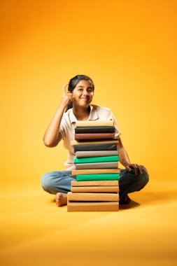 Kitap Yığını, Neşeli Hintli Genç Kız Sarı Kusursuz Özgeçmiş, Öğrenme, Okul Kavramları ve Akademik Mükemmellik Üzerine Eğitim Kitapları Yığını 'nda Mutlulukla Gösteriyor