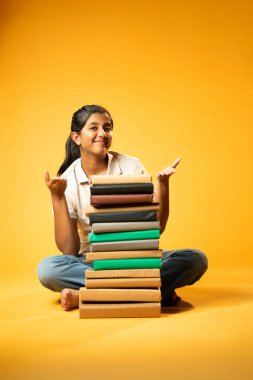 Kitap Yığını, Neşeli Hintli Genç Kız Sarı Kusursuz Özgeçmiş, Öğrenme, Okul Kavramları ve Akademik Mükemmellik Üzerine Eğitim Kitapları Yığını 'nda Mutlulukla Gösteriyor