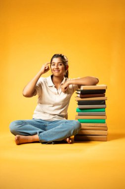 Kitap Yığını, Neşeli Hintli Genç Kız Sarı Kusursuz Özgeçmiş, Öğrenme, Okul Kavramları ve Akademik Mükemmellik Üzerine Eğitim Kitapları Yığını 'nda Mutlulukla Gösteriyor