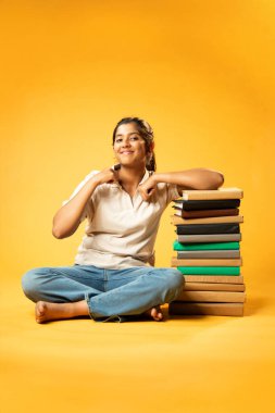 Kitap Yığını, Neşeli Hintli Genç Kız Sarı Kusursuz Özgeçmiş, Öğrenme, Okul Kavramları ve Akademik Mükemmellik Üzerine Eğitim Kitapları Yığını 'nda Mutlulukla Gösteriyor