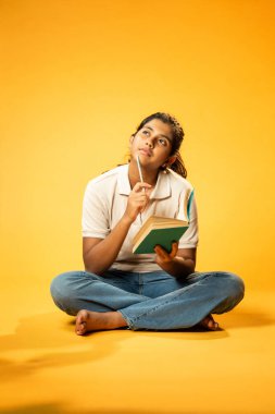 Kitap yazmakta, Hintli Asyalı Kız Derinlemesine Düşünerek Oturmakta ve Ders Çalışırken Not Almakta, Odaklanma ve Merakı Göstermekte Öğrenme veya Ödevde Etkinlik Göstermekte