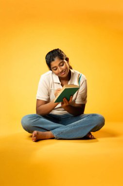 Kitap yazmakta, Hintli Asyalı Kız Derinlemesine Düşünerek Oturmakta ve Ders Çalışırken Not Almakta, Odaklanma ve Merakı Göstermekte Öğrenme veya Ödevde Etkinlik Göstermekte