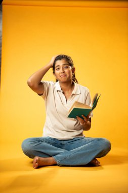 Kitap Okuma, Gergin Hintli Genç Kız Sarı Kusursuz Arkaplanda Oturarak Endişe Gösteriyor, Sınav ve Korku Duyuyor Üzgün Yüz İfadesi ve Düşük Özgüven ile Yalnız Çalışırken