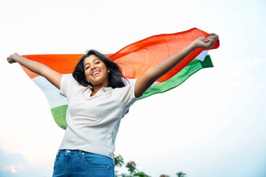 Elinde Hint Bayrağı, Neşeli Genç Kız Rüzgarda Üç Renkli Flütçüler, Mavi Gökyüzü Altında Ulusal Gurur ve Vatanseverlik Gösteren Mutlu Asyalı Çocuk
