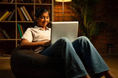 Huysuz Lamba Tuğla Duvara Karşı Evdeyken Laptop kullanan Hintli genç kız, Konforlu Çevrede Ödev Yapmaya ya da Çalışmaya Odaklandı