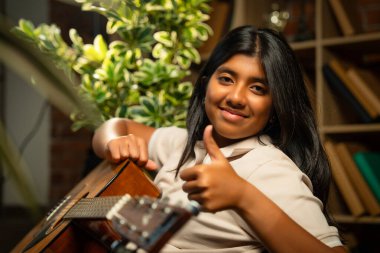 Kederli Lamba ile Sıcak Oda 'da Otururken Gitarlı Kız Pozu Tuğla Duvara Karşı Huysuz Lamba, Hint Genç Müzisyen Yazı, Beste veya Evde Evde Yalnız Akustik Müzik Çalıyor