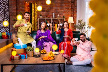 Arkadaşlar Diwali 'yi çay, Hint Asyalı aile ve geleneksel şenlik kıyafetleriyle kutluyorlar. Hint festivali Deepavali' nin tadını çıkarıyorlar. Süslü evde çay ya da kahveyi klasik bir çömlekle yudumluyorlar.