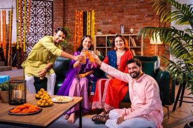 Soğuk bir içecekle Diwali kutlaması, Hintli genç evli çift ve geleneksel şenlik kıyafetleriyle Hindu festivalini süslenmiş evde portakal suyu veya meyve suyuyla kutluyorlar.