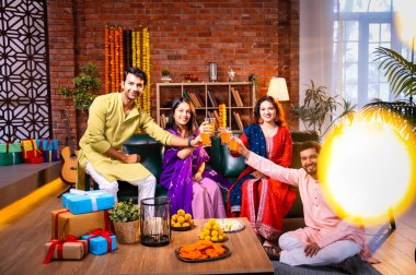 Soğuk bir içecekle Diwali kutlaması, Hintli genç evli çift ve geleneksel şenlik kıyafetleriyle Hindu festivalini süslenmiş evde portakal suyu veya meyve suyuyla kutluyorlar.