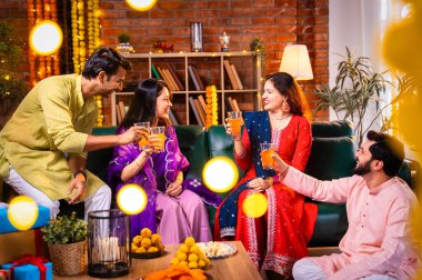 Soğuk bir içecekle Diwali kutlaması, Hintli genç evli çift ve geleneksel şenlik kıyafetleriyle Hindu festivalini süslenmiş evde portakal suyu veya meyve suyuyla kutluyorlar.