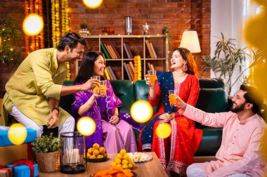 Soğuk bir içecekle Diwali kutlaması, Hintli genç evli çift ve geleneksel şenlik kıyafetleriyle Hindu festivalini süslenmiş evde portakal suyu veya meyve suyuyla kutluyorlar.