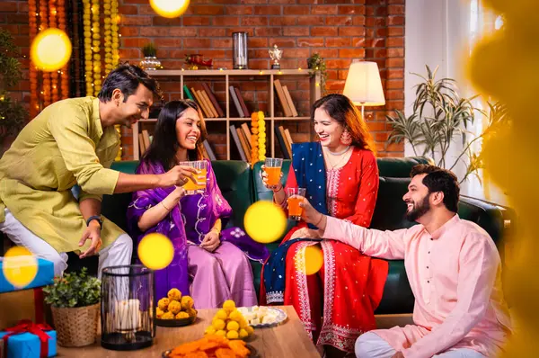 Soğuk bir içecekle Diwali kutlaması, Hintli genç evli çift ve geleneksel şenlik kıyafetleriyle Hindu festivalini süslenmiş evde portakal suyu veya meyve suyuyla kutluyorlar.