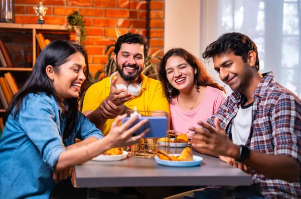 Kafede komik videolar izliyorlar, Hintli Asyalı genç üniversite arkadaşları ya da üniversite öğrencileri samosa yerken yüksek sesle gülüyorlar, sıcak çay yudumluyorlar, kapalı alanda komedi kliplerinin keyfini çıkarıyorlar.