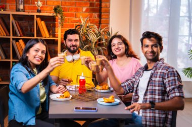 Hintli arkadaşlar sıcak çayın keyfini çıkarıyorlar, Asyalı genç üniversite öğrencileri kapalı bir lokantada oturmuş çay içiyor ya da cam bardaklardan kahve içiyor, arkadaşça sohbetler sırasında gülümsüyor ve kaynaşıyorlar.