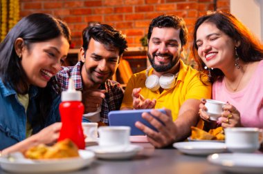 Kafede komik videolar izliyorlar, Hintli Asyalı genç üniversite arkadaşları ya da üniversite öğrencileri samosa yerken yüksek sesle gülüyorlar, sıcak çay yudumluyorlar, kapalı alanda komedi kliplerinin keyfini çıkarıyorlar.