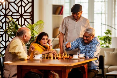 Hindistan 'daki son sınıf yetişkinler rahat bir evde yemek masasında oturmuş satranç oynarken gülümsüyor ve Shatranj maçının keyfini çıkarırken Asyalı eski dostlar kapalı alanda yeniden bir araya gelişlerini kutluyorlar.