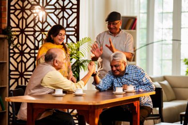 Hint son sınıf öğrencileri yemek masasında bilek güreşi ya da dostça panja oyunu oynuyorlar, ev içinde neşeyle yarışıyorlar, Asyalı yaşlı adamlar evde eğlenirken eğleniyorlar ve tezahürat yapıyorlar.