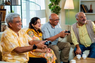 Modern Hint Asya evindeki rahat koltukta oturan son sınıf öğrencileri eğlence, arkadaşça rekabet, kahkaha ve dijital eğlence için bir araya geliyorlar.