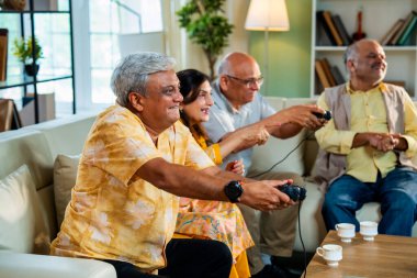 Modern Hint Asya evindeki rahat koltukta oturan son sınıf öğrencileri eğlence, arkadaşça rekabet, kahkaha ve dijital eğlence için bir araya geliyorlar.