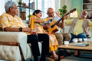 Son sınıflar rahat koltukta oturup gitar çalarken şarkı söylüyorlar. Dört arkadaşından oluşan Hintli Asyalı bir grup içeride neşeyle bir araya geliyor. Müzikal bağın ve modern evdeki mutlu anların tadını çıkarıyorlar.