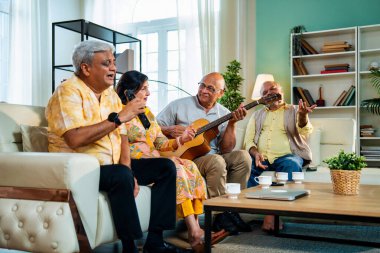 Son sınıflar rahat koltukta oturup gitar çalarken şarkı söylüyorlar. Dört arkadaşından oluşan Hintli Asyalı bir grup içeride neşeyle bir araya geliyor. Müzikal bağın ve modern evdeki mutlu anların tadını çıkarıyorlar.