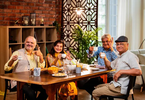 Son sınıflar birlikte yemek yiyor, Hintli Asyalı yaşlı arkadaşlar evde bir araya geliyor, yemek yiyor, atıştırmalık, soğuk içecek, çay ya da kahve servisi yapıyor, modern yemek masasında oturmuş, eğleniyorlar.