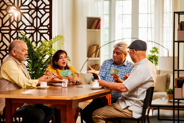 Hindistan 'daki son sınıf öğrencileri, rahat, modern bir evde yemek masasında oturmuş, neşeli bir şekilde gülüyor ve kaynaşıyorlar. Asyalı yaşlı arkadaşlar, kapalı alanda eğlenceli aktivitelerle neşeli bir buluşmayı kutluyorlar.