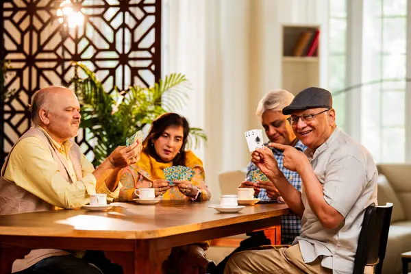 Hindistan 'daki son sınıf öğrencileri, rahat, modern bir evde yemek masasında oturmuş, neşeli bir şekilde gülüyor ve kaynaşıyorlar. Asyalı yaşlı arkadaşlar, kapalı alanda eğlenceli aktivitelerle neşeli bir buluşmayı kutluyorlar.