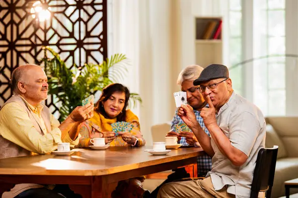 Hindistan 'daki son sınıf öğrencileri, rahat, modern bir evde yemek masasında oturmuş, neşeli bir şekilde gülüyor ve kaynaşıyorlar. Asyalı yaşlı arkadaşlar, kapalı alanda eğlenceli aktivitelerle neşeli bir buluşmayı kutluyorlar.