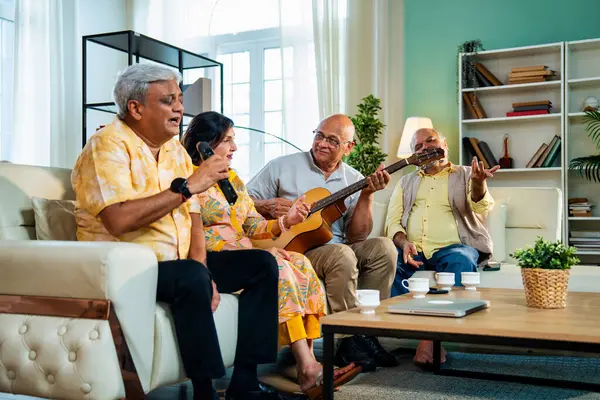 Son sınıflar rahat koltukta oturup gitar çalarken şarkı söylüyorlar. Dört arkadaşından oluşan Hintli Asyalı bir grup içeride neşeyle bir araya geliyor. Müzikal bağın ve modern evdeki mutlu anların tadını çıkarıyorlar.