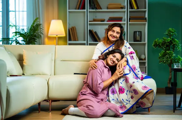 Yaşlı anne, kanepede otururken el ele tutuşarak sohbet ediyor. Hintli, Asyalı, sari giymiş yaşlı bir anne ve yanında oturan genç bir kız. Kapalı alanda samimi konuşmalar yapıyor.