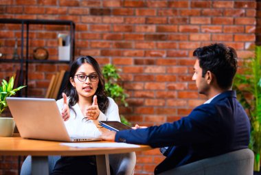 Hintli iş adamları dizüstü bilgisayar ve belge kullanıyorlar, Asyalı kurumsal erkek ve kadın resmi giyinmiş raporları tartışıyorlar, modern ofis masasında dizüstü bilgisayarla birlikte çalışıyorlar, takım çalışması kavramı.
