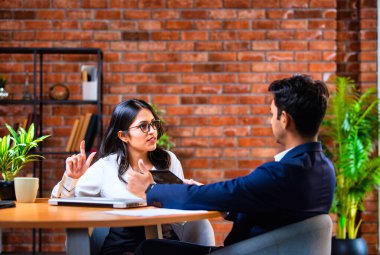 Hintli iş adamları dizüstü bilgisayar ve belge kullanıyorlar, Asyalı kurumsal erkek ve kadın resmi giyinmiş raporları tartışıyorlar, modern ofis masasında dizüstü bilgisayarla birlikte çalışıyorlar, takım çalışması kavramı.