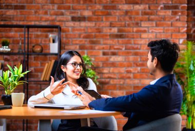 Hintli iş adamları dizüstü bilgisayar ve belge kullanıyorlar, Asyalı kurumsal erkek ve kadın resmi giyinmiş raporları tartışıyorlar, modern ofis masasında dizüstü bilgisayarla birlikte çalışıyorlar, takım çalışması kavramı.