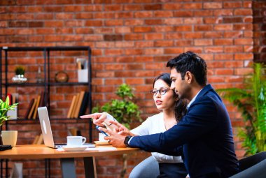 Hintli iş adamları dizüstü bilgisayar ve belge kullanıyorlar, Asyalı kurumsal erkek ve kadın resmi giyinmiş raporları tartışıyorlar, modern ofis masasında dizüstü bilgisayarla birlikte çalışıyorlar, takım çalışması kavramı.