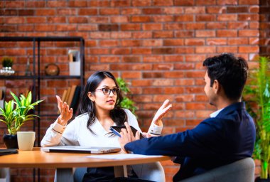 Hintli iş adamları dizüstü bilgisayar ve belge kullanıyorlar, Asyalı kurumsal erkek ve kadın resmi giyinmiş raporları tartışıyorlar, modern ofis masasında dizüstü bilgisayarla birlikte çalışıyorlar, takım çalışması kavramı.