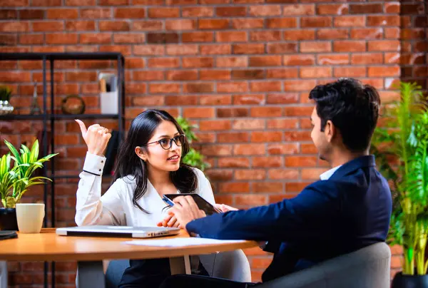 Hintli iş adamları dizüstü bilgisayar ve belge kullanıyorlar, Asyalı kurumsal erkek ve kadın resmi giyinmiş raporları tartışıyorlar, modern ofis masasında dizüstü bilgisayarla birlikte çalışıyorlar, takım çalışması kavramı.