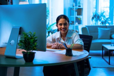 İş kadını, iş molasında kahve fincanı içerken telefon kullanıyor, Hintli Asyalı kadın profesyonel çalışma masasında duruyor, gülümsüyor ve elinde içki içerken akıllı telefonuyla meşgul oluyor.