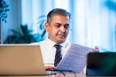 Hintli işadamı, şirket kaybını, stresi, gerilimi ve baskıyı temsil eden finansal belgeleri analiz eden Asyalı şirket yöneticisi, modern ofiste masa başında otururken raporları okumaktan endişe duyuyordu.