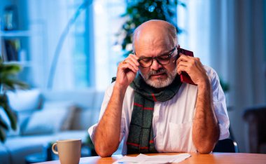 Hintli üst düzey bir adam, vergi raporlarını evde, masada CA ile görüşüyor. Gelir vergisi doldurma sezonunda muhasebeciye danışırken mutlu, yaşlı bir insan gülümsüyor.