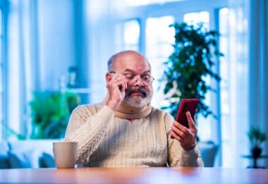 Hintli son sınıf öğrencisi evde çay içerken akıllı telefon kullanıyor, rahat yaşlı bir insan rahat bir şekilde cep telefonuna bakarken rahat bir şekilde sabah içkisinin keyfini çıkarıyor.